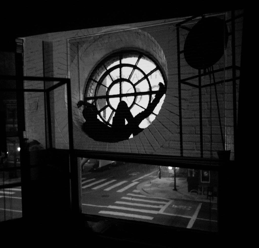 Projection of a man lying on a windowsill.
